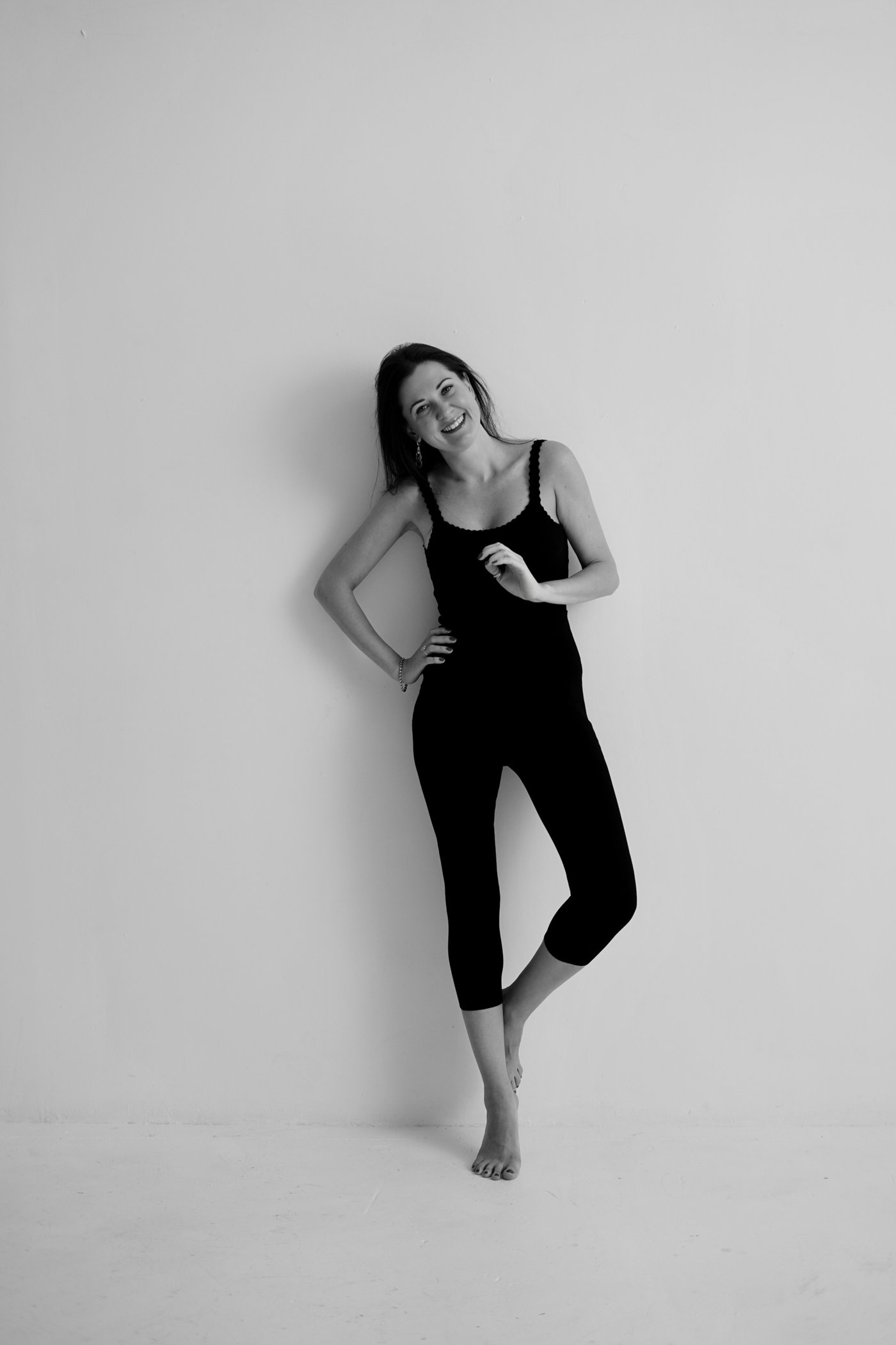 Anna smiling and laughing, leaning against a white wall